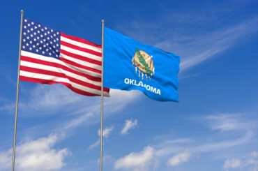 Oklahoma state flag and US flag on a clear sky