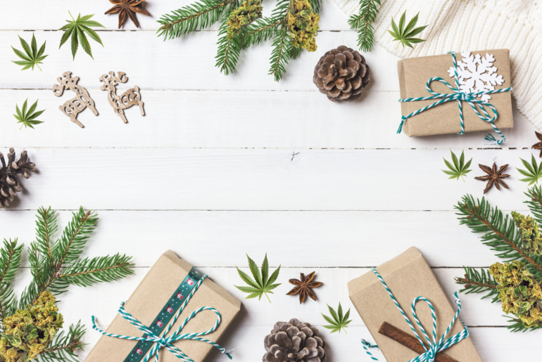 wrapped presents in a circle with seasonal greens and cannabis leaves